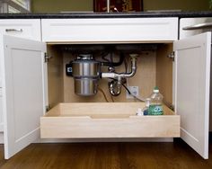 an open cabinet with a coffee maker and water bottle in the bottom drawer next to it