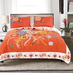 a bed with an orange comforter and pillows