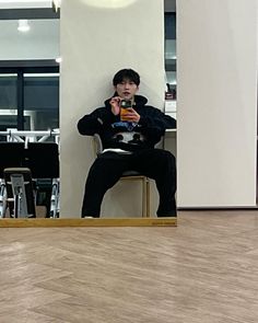 a man sitting in front of a mirror taking a selfie with his cell phone