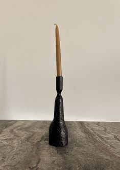 a black vase with a wooden stick sticking out of it's side on a table