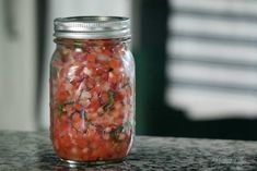 a glass jar filled with red onions on top of a counter