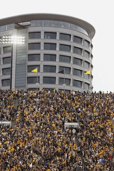 a large crowd of people in front of a building with yellow flags on the roof