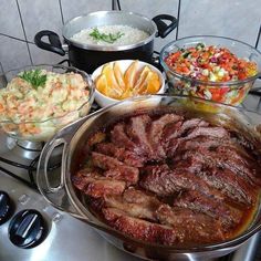 various foods are being prepared on the stove top, including meats and salads