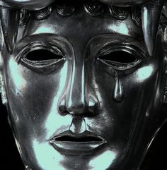 a close up of a silver mask on a black background