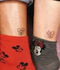 two people with matching mickey and minnie mouse tattoos on their legs