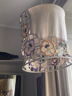 a lamp hanging from the ceiling next to a window with curtains in front of it