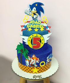 a sonic the hedgehog themed birthday cake on a wooden stool with a white wall in the background