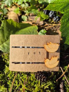 a wooden brooch sitting on top of green grass next to leaves and berries in the woods