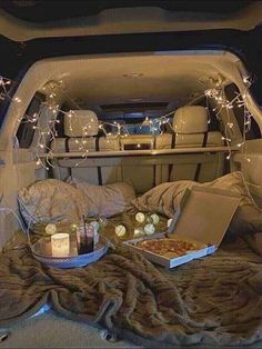 the back of an suv with food and candles in its trunk, on top of a blanket