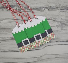 a green and white christmas ornament hanging from a string on a marble surface