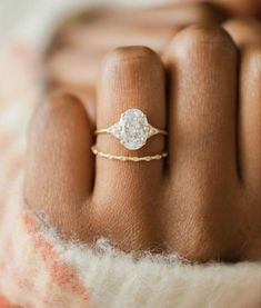 a woman's hand with a diamond ring on top of her finger, in the middle