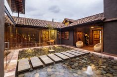 an outdoor courtyard with stone steps leading to the front door and water feature in the center