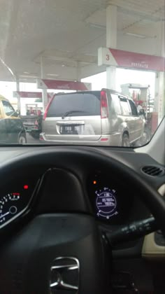 the dashboard of a car in front of a gas station with other cars parked nearby