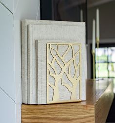 an open book sitting on top of a wooden table next to a candle holder with trees cut out of it