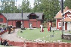 people are standing in front of a red building with horses and carriages on the lawn