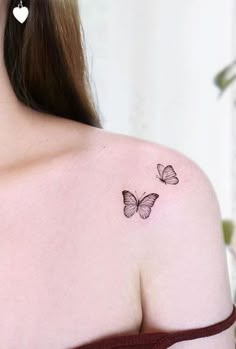 the back of a woman's shoulder with two butterflies on her left shoulder, and one