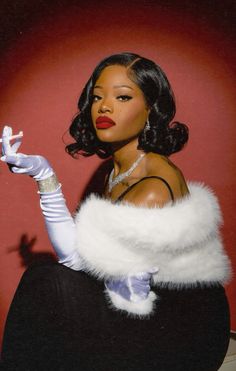 a woman sitting on top of a black chair wearing white gloves and a fur stole