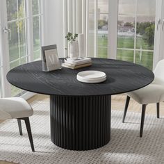 a black table with white chairs and a vase on it in front of a window