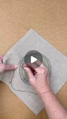 someone is working on a piece of paper with scissors and thread in it, while another person holds the edge of an object