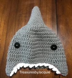 a crocheted shark hat with black buttons on it's eyes and mouth