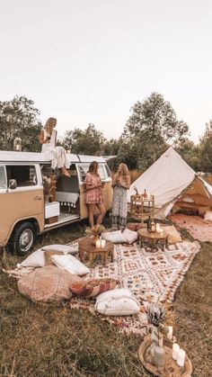 two women sitting on the back of a van with food and drinks in front of them