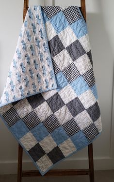 a blue and black checkered blanket sitting on top of a wooden chair next to a white wall