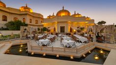 an outdoor dining area with tables and chairs in front of a domed building at dusk