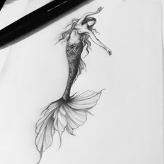 a pencil drawing of a mermaid with long hair and tail, sitting on top of a piece of paper