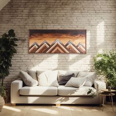 a white couch sitting in front of a brick wall next to a potted plant