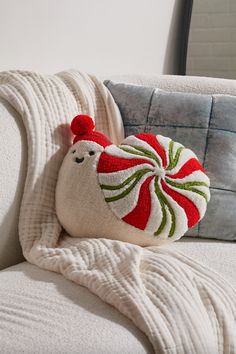 a white couch with a red and green decorative pillow on it's back side