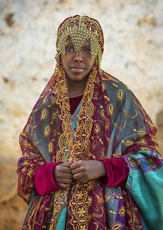 a young woman wearing a colorful dress and head scarf