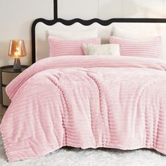 a bed with pink comforter and pillows on it