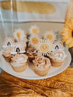 some cupcakes are on a plate with sunflowers and other decorations in the background