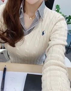 a woman sitting at a desk with a pen in her hand