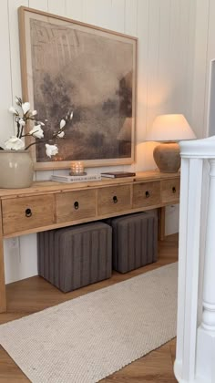 a wooden table with two baskets underneath it and a painting on the wall behind it