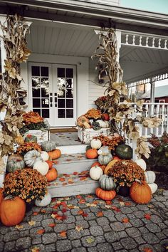 pumpkins and gourds are arranged on the porch