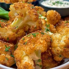 a bowl filled with fried cauliflower and broccoli next to dipping sauce