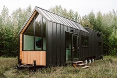 a tiny house in the middle of a field with stairs leading up to it's windows