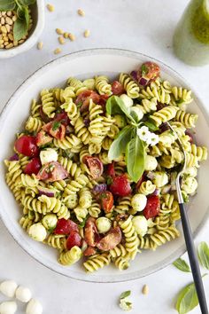 a white plate topped with pasta salad next to two bowls