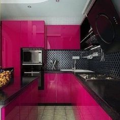 a kitchen with pink cabinets and black counter tops in the center, along with a bowl of fruit on the counter