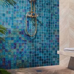 a bathroom with blue tiles on the wall and a gold faucet next to it