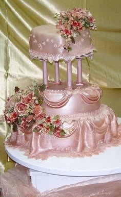 a three tiered wedding cake with pink flowers on the top and sides, sitting on a white platter