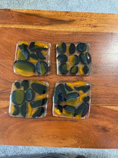 four square pieces of glass sitting on top of a wooden table next to a pair of black shoes