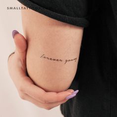 a woman's arm with the words forever young written on it, in cursive handwriting