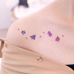 a woman's shoulder with purple flowers on the left side of her body and small white dots in the middle