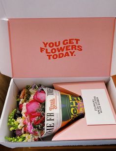 an open pink box with flowers in it and a card inside that says, you get flowers today