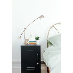 a black cabinet sitting on top of a wooden floor next to a bed and a lamp