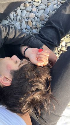 a man laying on the ground with his head in his hands and another hand holding something