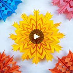 colorful origami flowers are arranged on a white surface with an arrow in the center