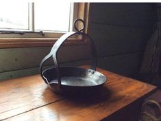 an iron skillet sitting on top of a wooden table next to a window in a room